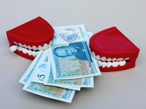 Fake teeth chomping on money